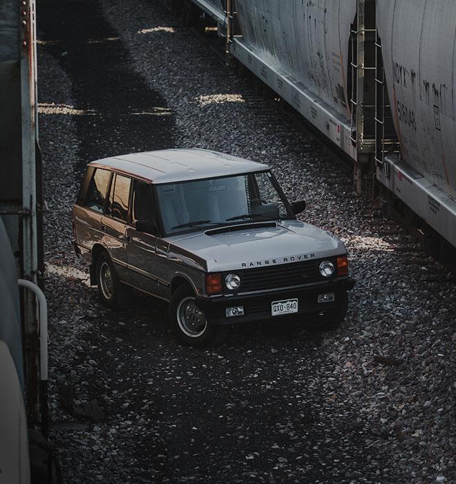 Land Rover Ranger Rover Classic parked between two trains in a train yard