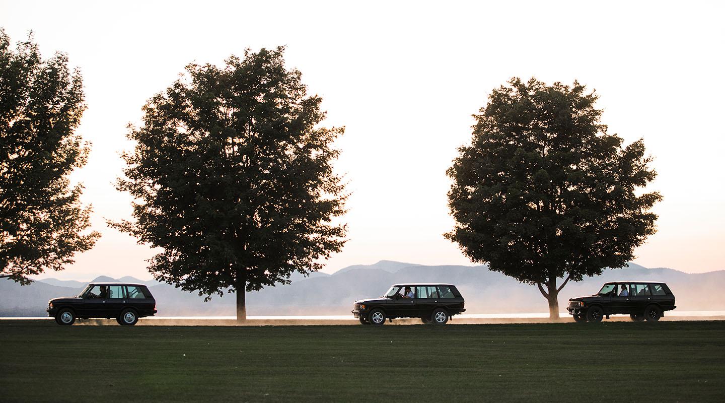 Three 1995 Range Rover Classics driving on a dirt road with mountains in the background