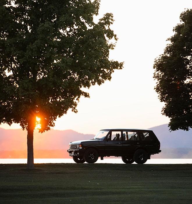 1995 Range Rover Classic parked on a dirt road with mountains in the background