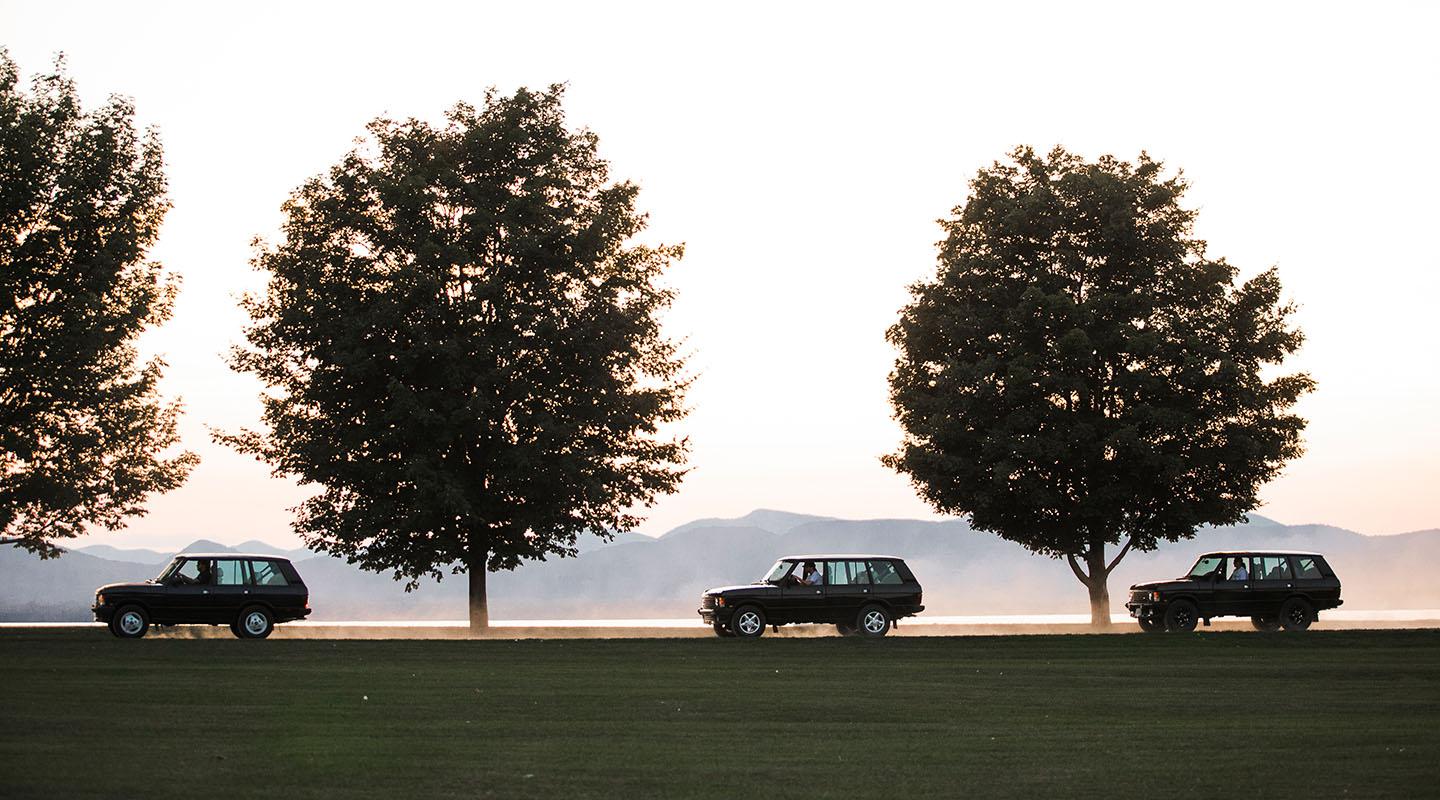 Three Range Rover Classics driving down a dirt road with mountains in the background